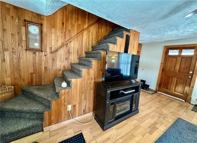 stairway featuring a textured ceiling, wood finished floors, and wood walls