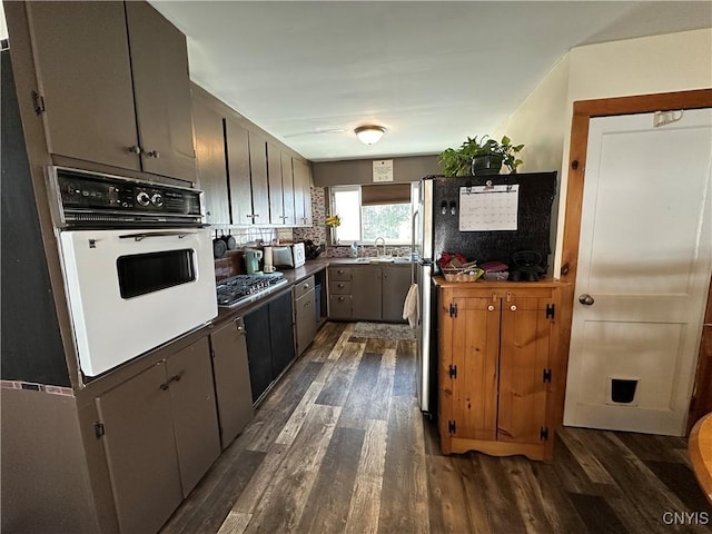 kitchen with oven, tasteful backsplash, stainless steel gas stovetop, and dark wood-style flooring