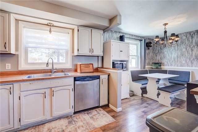 kitchen featuring a sink, stainless steel appliances, a healthy amount of sunlight, and wallpapered walls