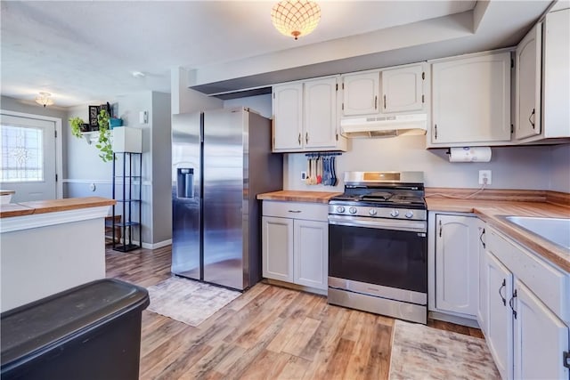 kitchen featuring under cabinet range hood, butcher block countertops, appliances with stainless steel finishes, and light wood-type flooring