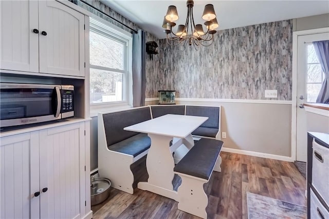 dining area featuring wallpapered walls, an inviting chandelier, and wood finished floors