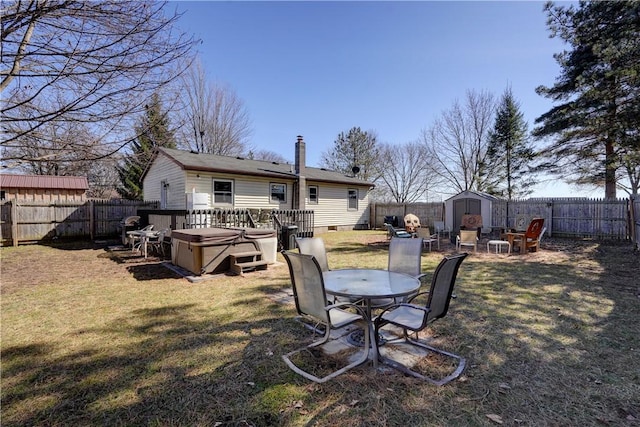 view of yard with an outbuilding, a shed, a hot tub, and a fenced backyard