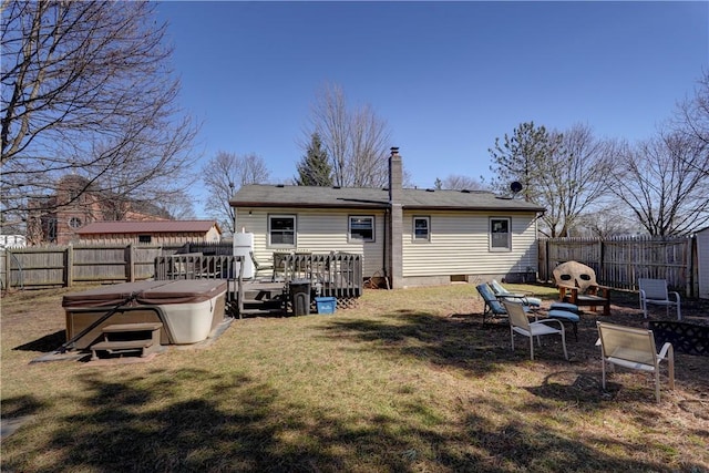 back of house featuring a yard, a wooden deck, a hot tub, and a fenced backyard