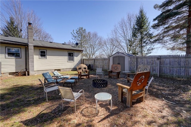 view of yard featuring a storage shed, an outdoor structure, a fire pit, and a fenced backyard