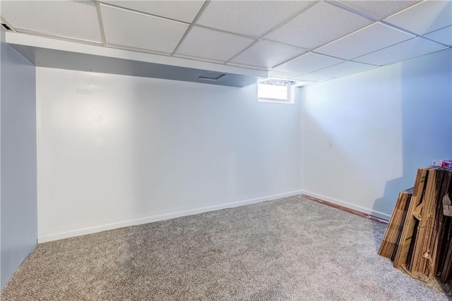 below grade area with a drop ceiling, baseboards, and carpet flooring