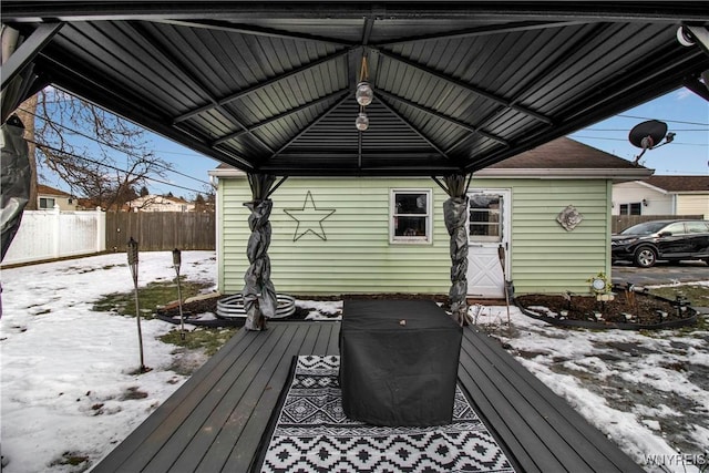 snow covered deck featuring a gazebo and fence