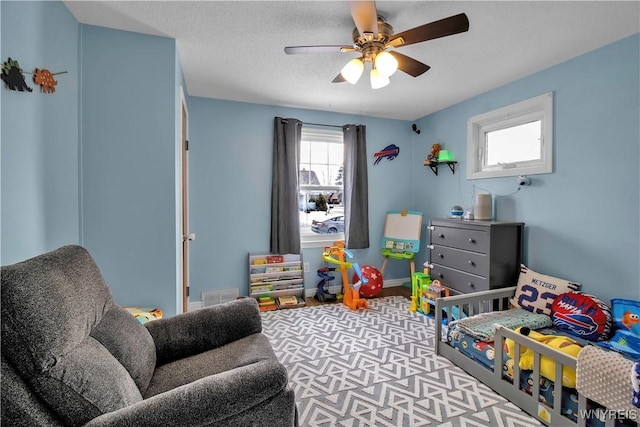 bedroom featuring ceiling fan, baseboards, visible vents, and a textured ceiling