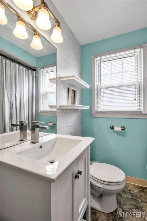 full bathroom with baseboards, plenty of natural light, toilet, and vanity