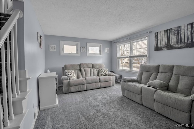 carpeted living area featuring stairway, a textured ceiling, and baseboards