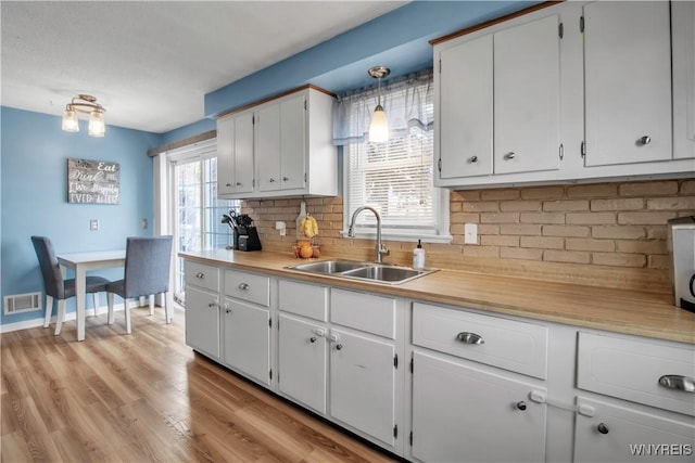 kitchen featuring decorative backsplash, light countertops, visible vents, and a sink