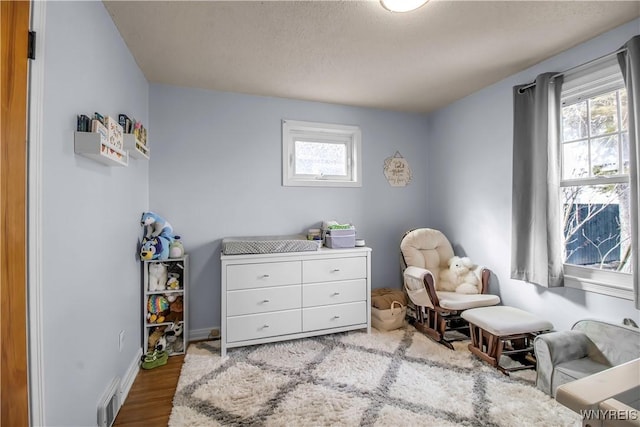 sitting room with visible vents, baseboards, and wood finished floors