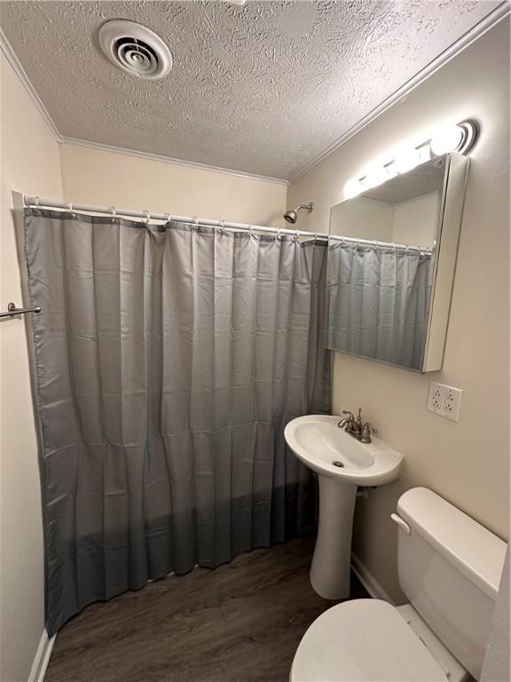 bathroom with visible vents, toilet, and wood finished floors