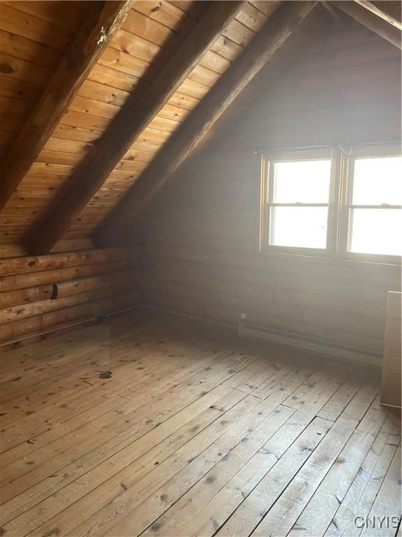 additional living space with wood ceiling, rustic walls, vaulted ceiling with beams, and wood-type flooring