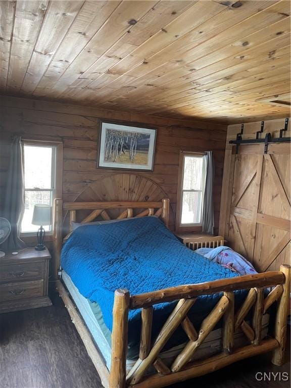 bedroom featuring multiple windows, wooden ceiling, a barn door, and wood finished floors