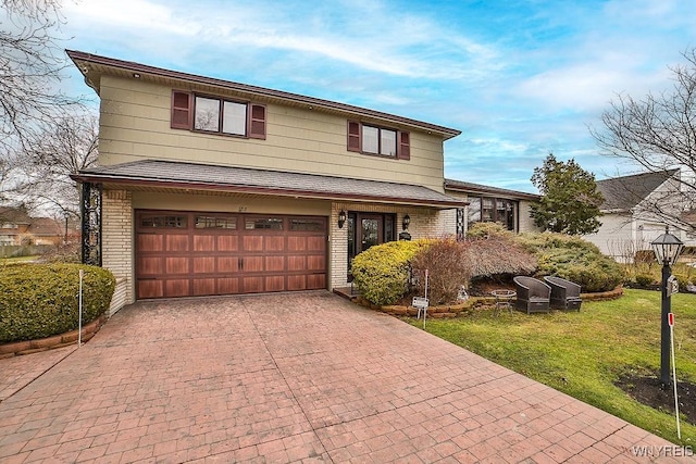 tri-level home with brick siding, an attached garage, decorative driveway, and a front lawn