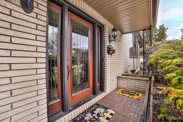 entrance to property featuring brick siding and covered porch