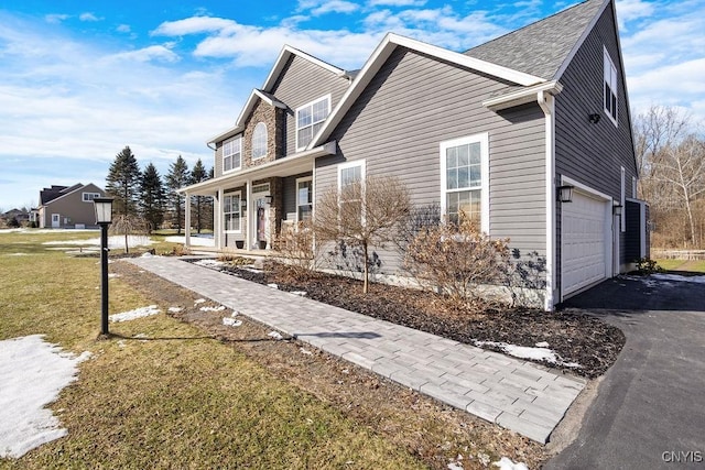 view of home's exterior with a yard, a garage, covered porch, and driveway