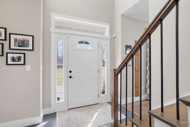 entrance foyer featuring stairway, baseboards, wood finished floors, and a towering ceiling