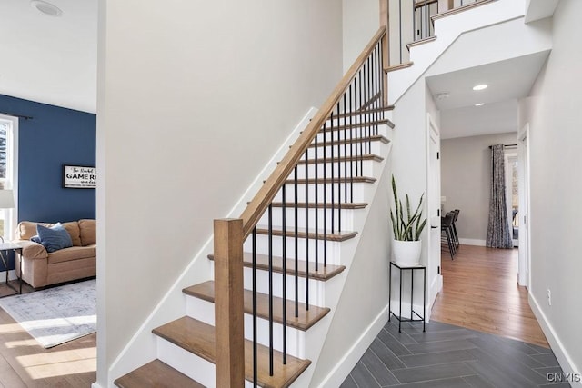 stairs with baseboards, a high ceiling, and wood finished floors