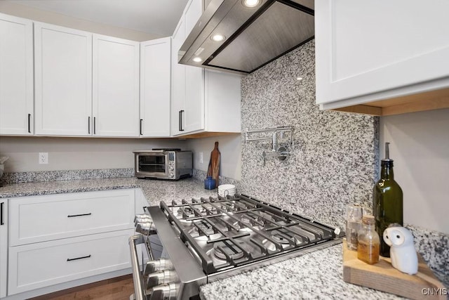 kitchen with backsplash, exhaust hood, white cabinets, and a toaster