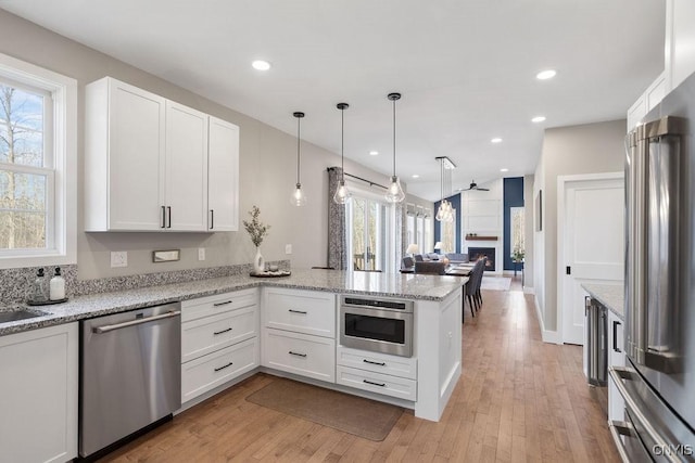 kitchen with appliances with stainless steel finishes, white cabinetry, and a peninsula