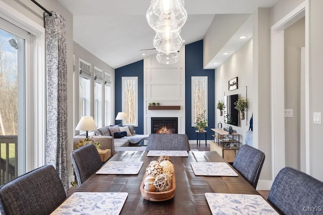 dining space featuring a fireplace, baseboards, and vaulted ceiling