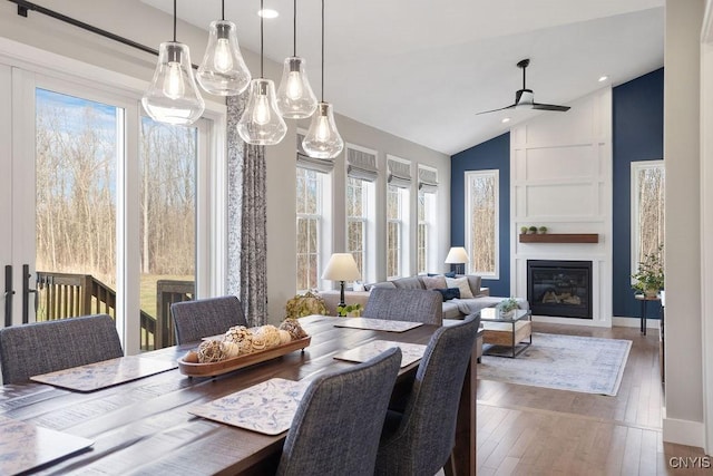 dining room with plenty of natural light, high vaulted ceiling, wood-type flooring, and a fireplace