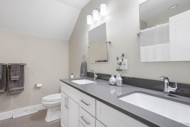 bathroom with vaulted ceiling, toilet, visible vents, and a sink