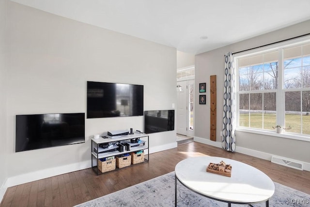 living area featuring plenty of natural light, visible vents, and wood finished floors