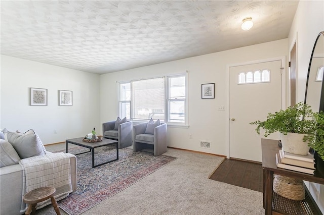 living area with baseboards, visible vents, and a textured ceiling