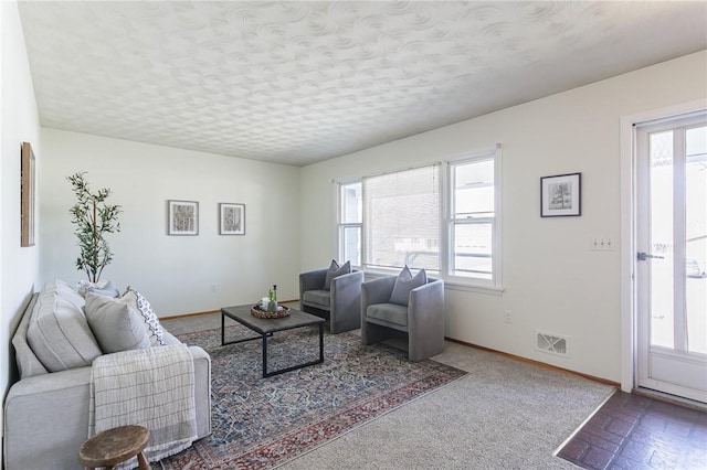 living room with visible vents, a healthy amount of sunlight, a textured ceiling, and baseboards