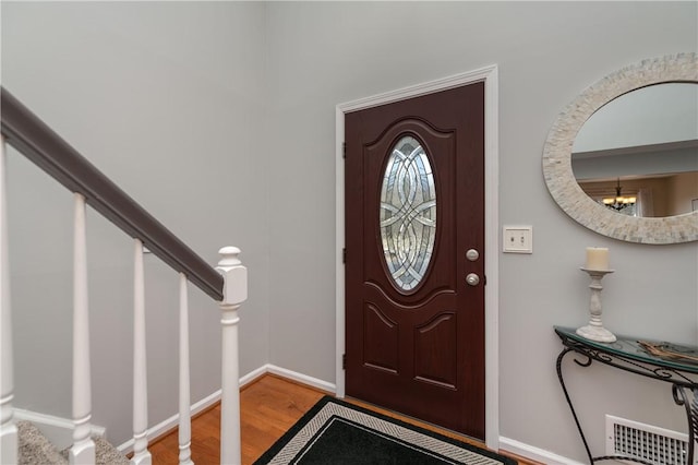 foyer entrance with visible vents, stairway, baseboards, and wood finished floors