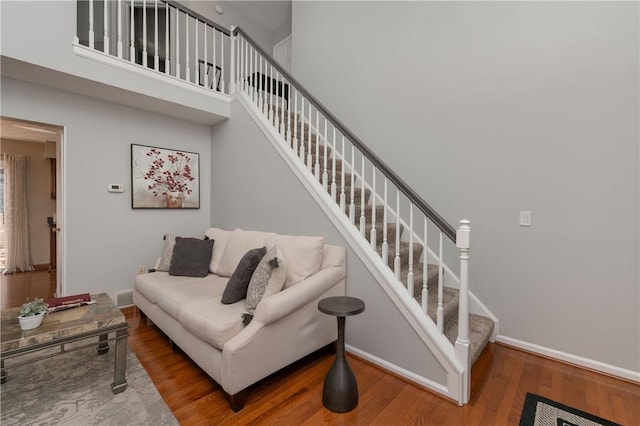 staircase featuring visible vents, baseboards, wood finished floors, and a towering ceiling