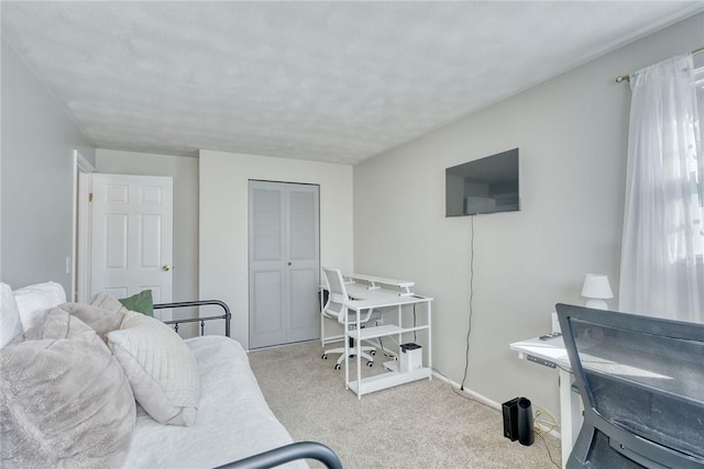 carpeted bedroom featuring a closet and baseboards