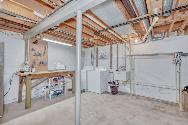 unfinished basement with a sink, a workshop area, and independent washer and dryer