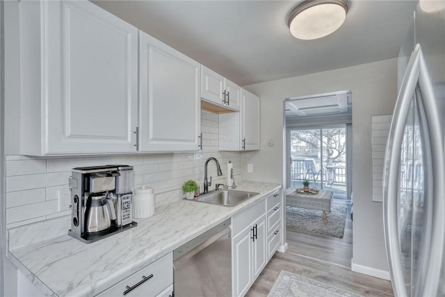 kitchen with a sink, tasteful backsplash, stainless steel appliances, white cabinets, and light wood finished floors