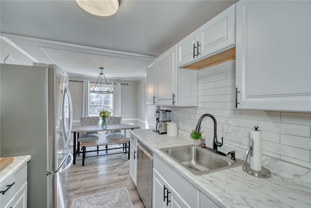 kitchen featuring a sink, decorative backsplash, stainless steel appliances, white cabinets, and light wood-type flooring