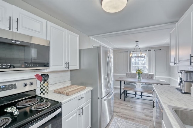 kitchen with backsplash, light stone countertops, appliances with stainless steel finishes, light wood-style floors, and white cabinets