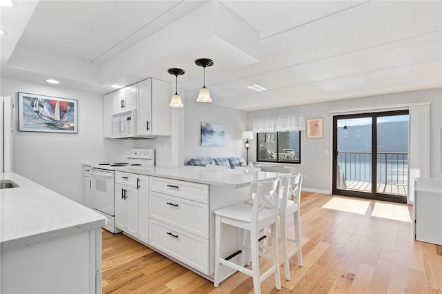 kitchen featuring white cabinets, white appliances, light wood-type flooring, and a peninsula