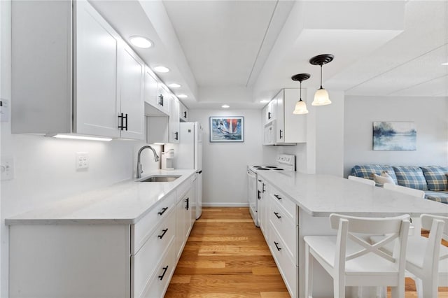 kitchen with light wood-style flooring, a sink, open floor plan, white appliances, and a peninsula