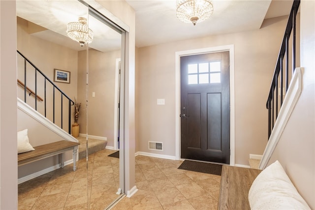 entryway with a chandelier, visible vents, stairs, and baseboards