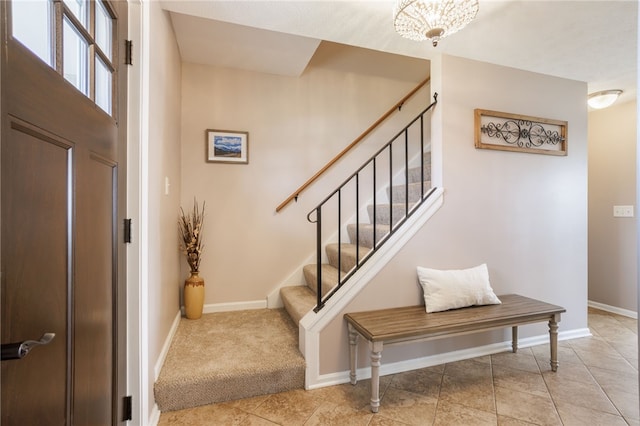 carpeted entrance foyer featuring stairway, baseboards, and tile patterned flooring