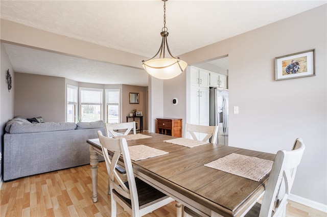 dining area featuring light wood-style flooring and baseboards