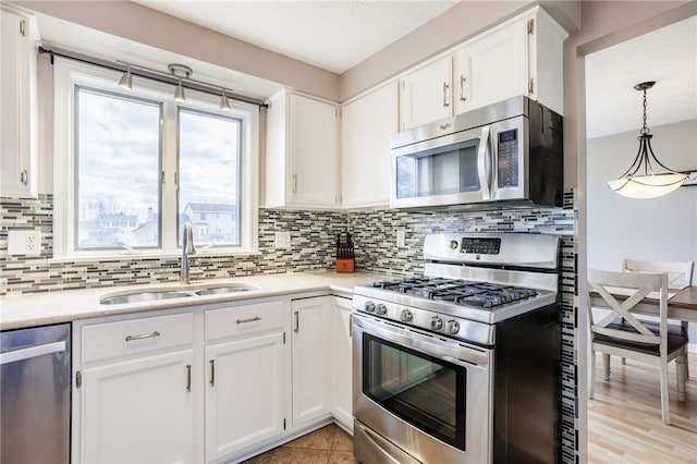 kitchen with light countertops, decorative backsplash, stainless steel appliances, white cabinetry, and a sink