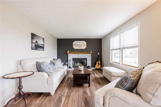 living room with baseboards, a brick fireplace, and wood finished floors