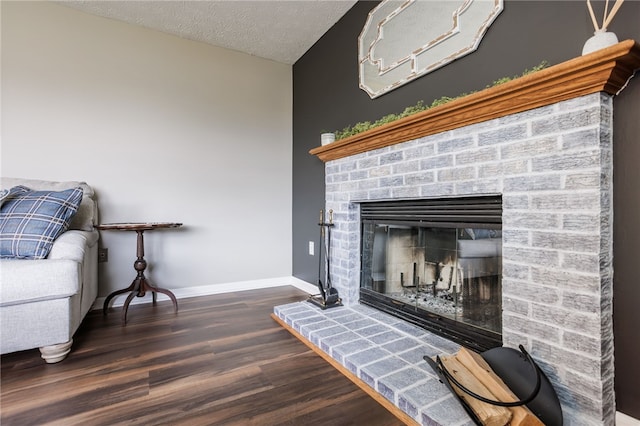 interior details featuring a fireplace, a textured ceiling, baseboards, and wood finished floors