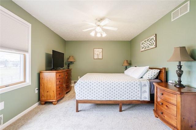 bedroom with visible vents, light carpet, baseboards, and a ceiling fan