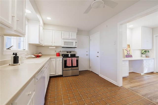 kitchen with white cabinetry, white appliances, light countertops, and built in desk