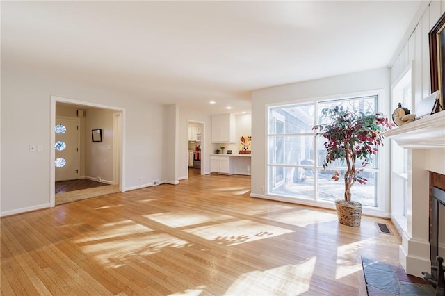 unfurnished living room with visible vents, a fireplace, light wood-type flooring, and baseboards