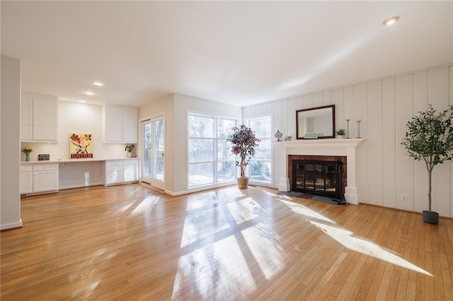 unfurnished living room featuring a brick fireplace, recessed lighting, and light wood-type flooring